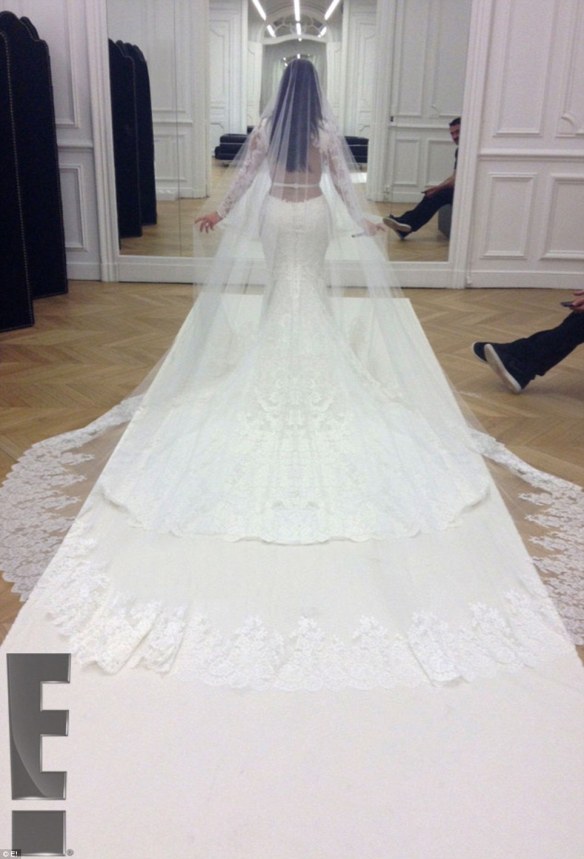 Kim walks down the aisle in her backless dress, long-sleeved with a train. Check out the flowing white cathedral-length veil. Her hair was worn loose and long. 